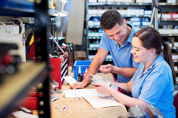 Engineer And Apprentice Examining Component At Workbench On site tool room training